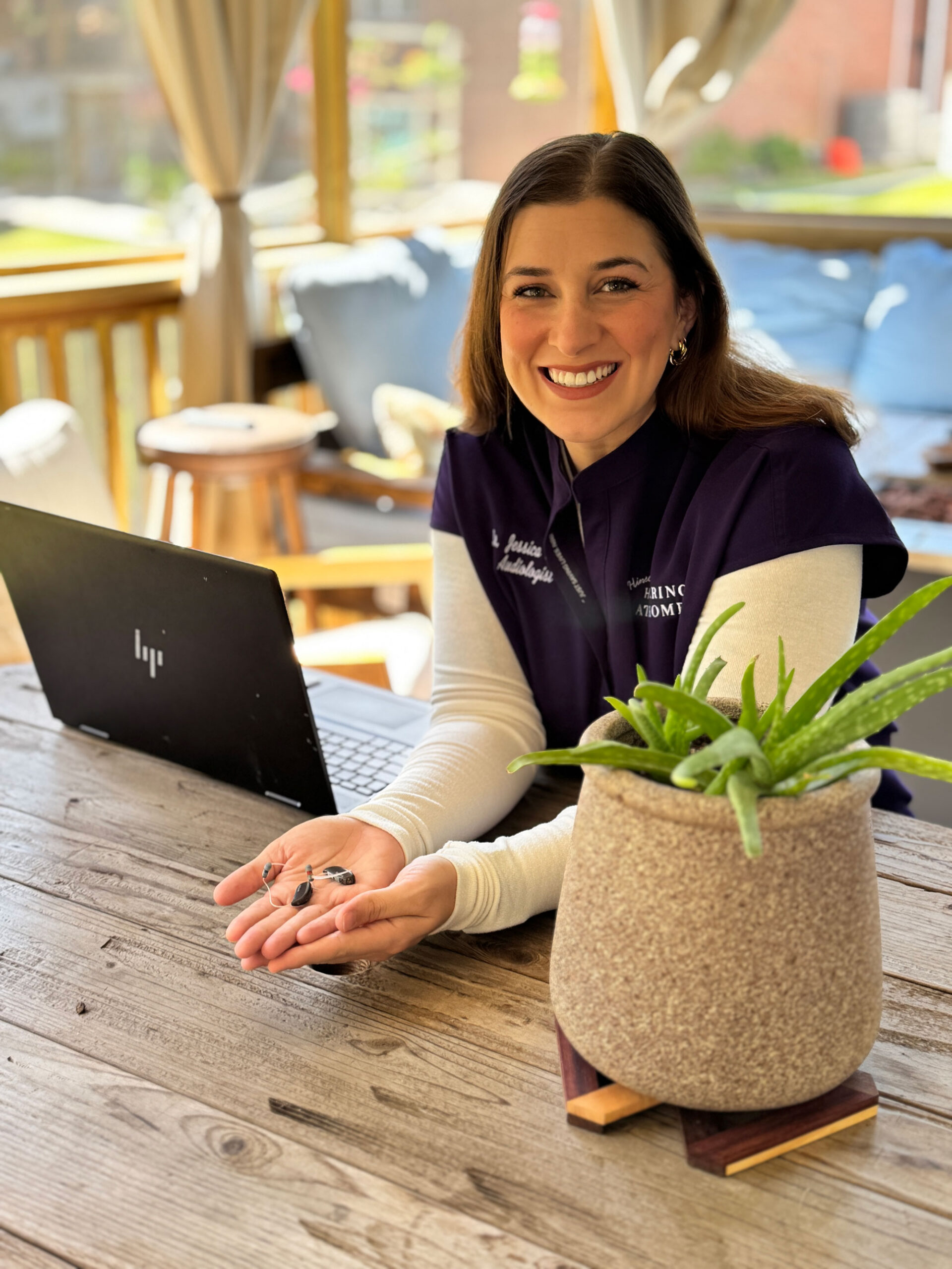 dr jessica hinson holding hearing aids smiling