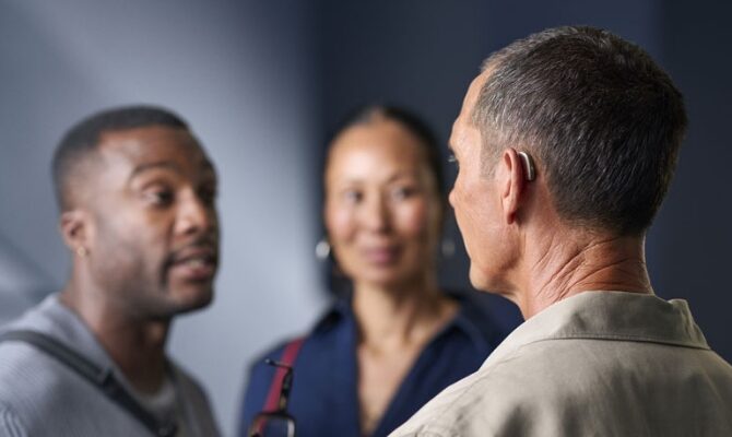small content man wearing hearing aids during group discussion