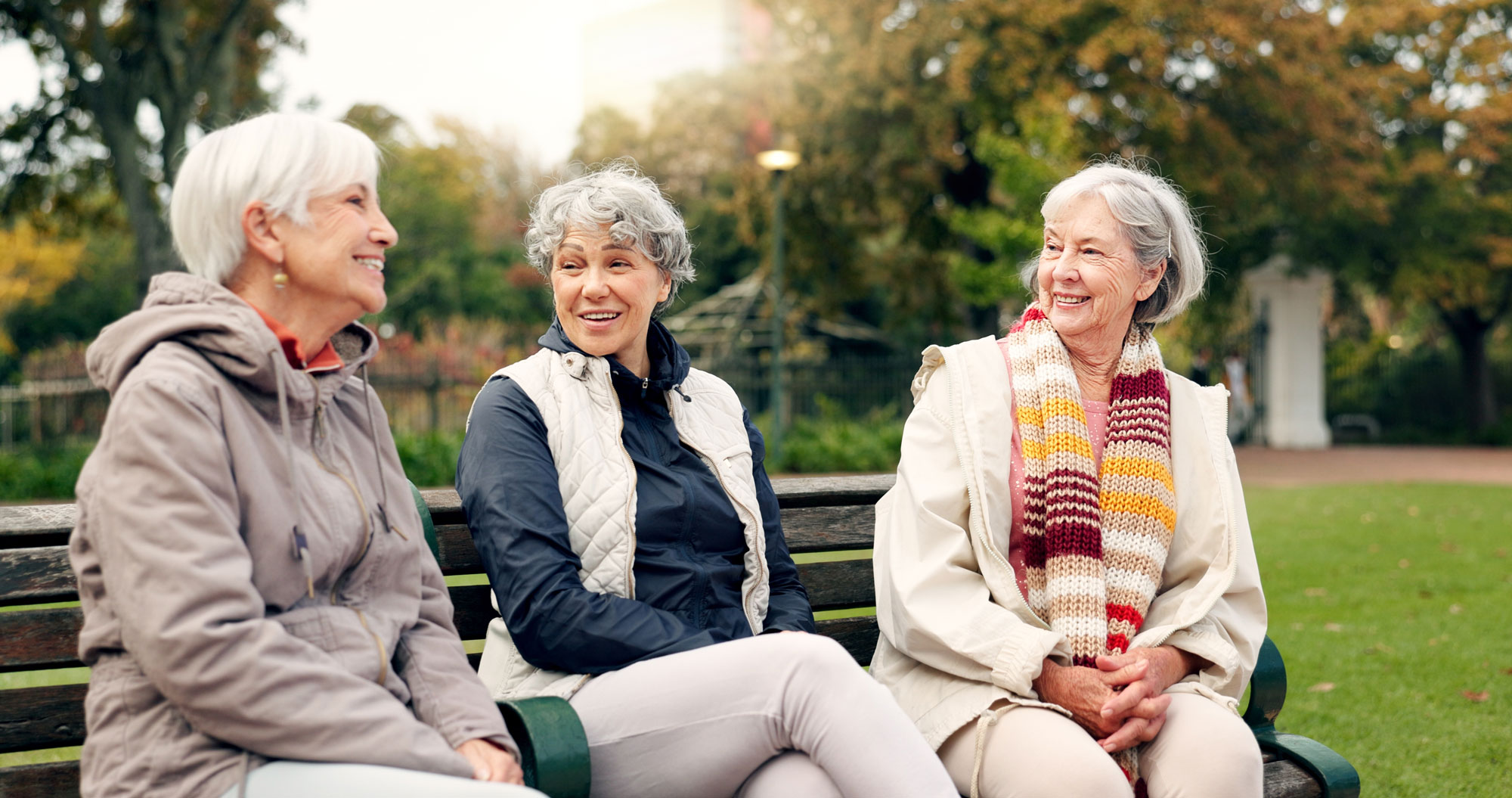 senior women friends talking on park bench