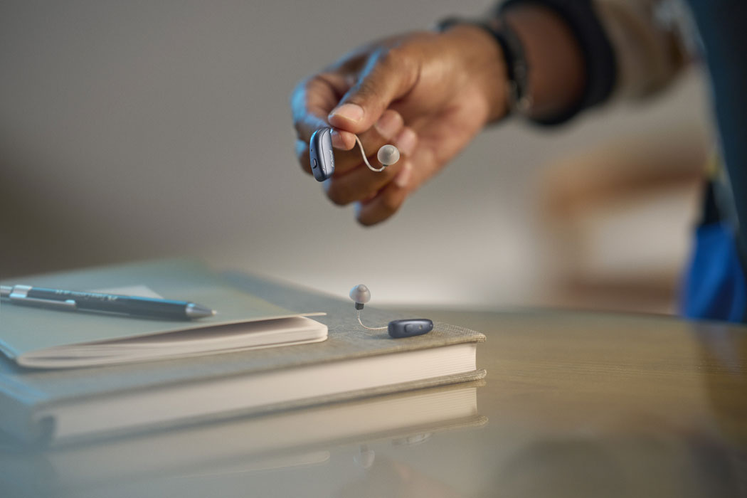 ReSound Vivia lifestyle holding hearing aids lifestyle warm grey