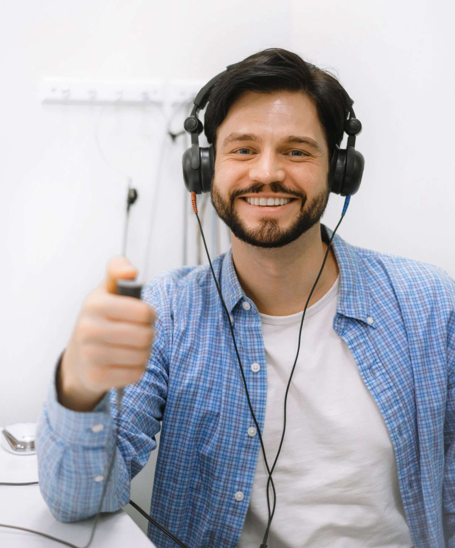man wearing headphones and pressing response button during pure tone audiometry
