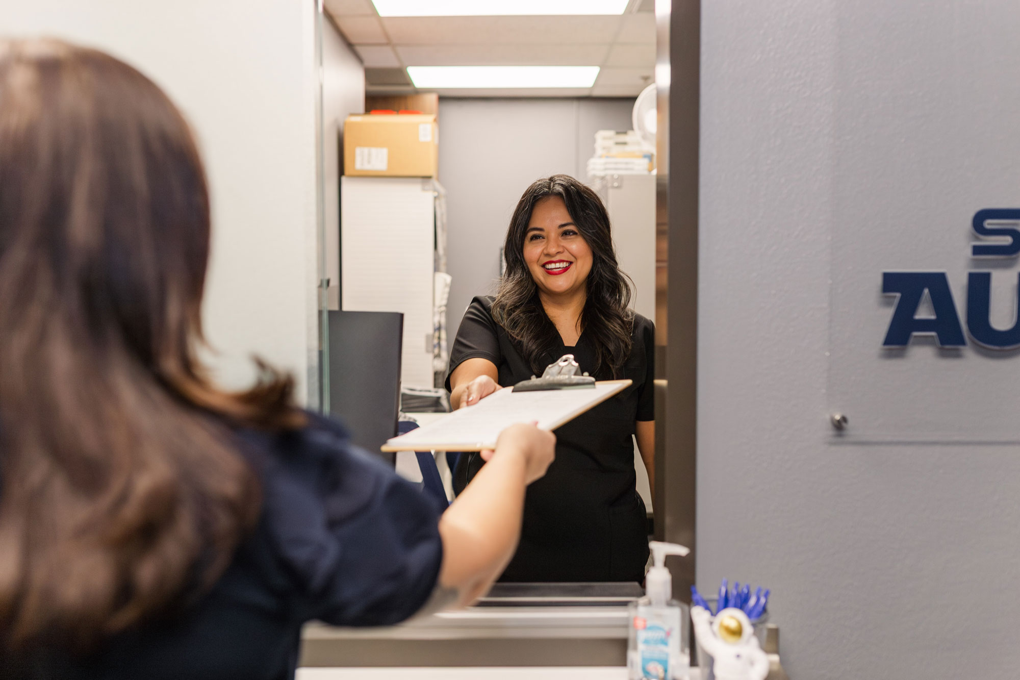 Space City Audiology 2 team member handing documents to patient