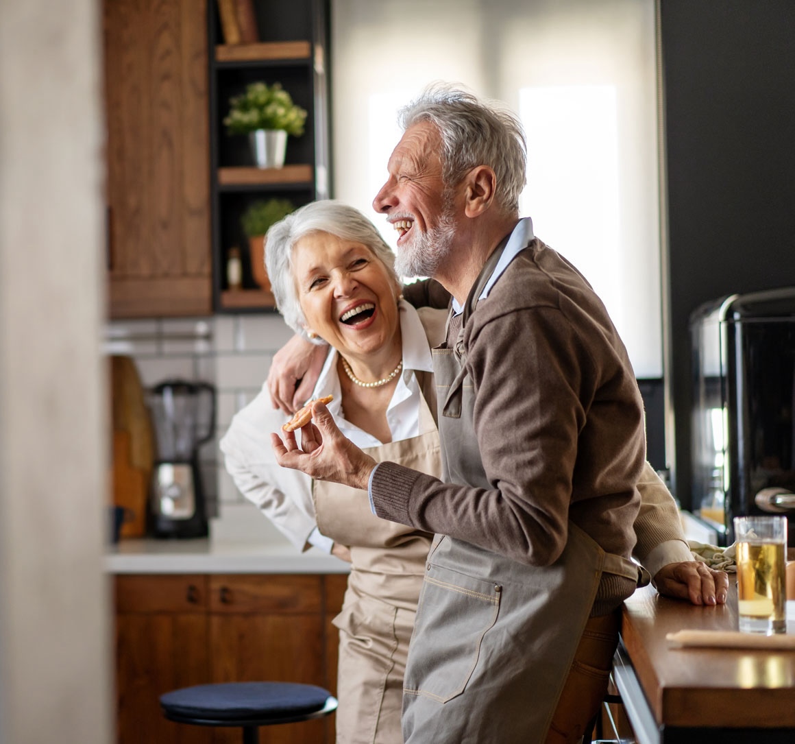 married couple baking cookies together in kitchen laughing square