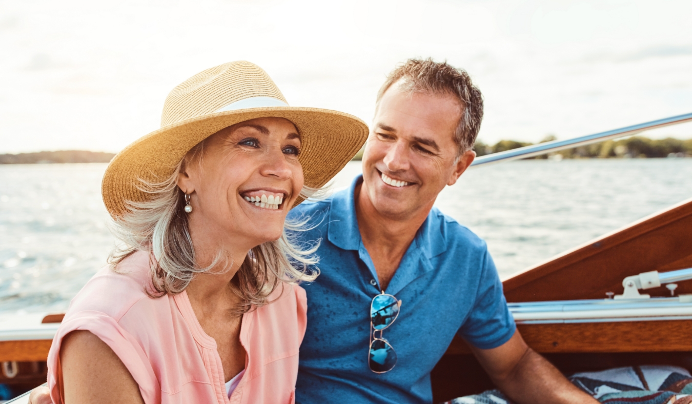 middle aged white couple smiling riding boat on lake