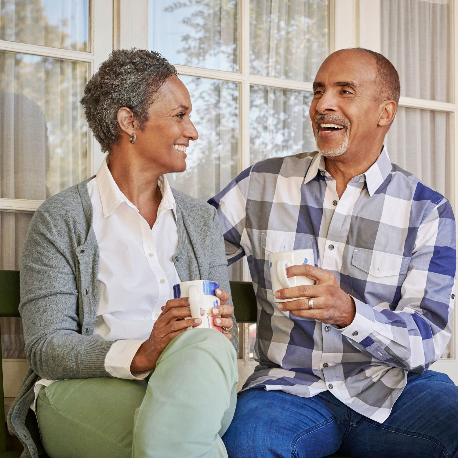 senior couple drinking coffee on porch laughing