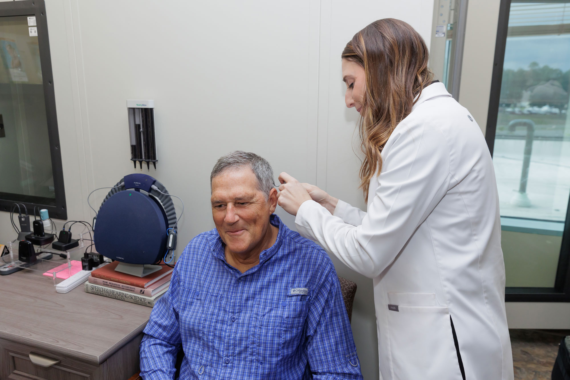 The Hearing Center provider placing cochlear hearing device on senior man