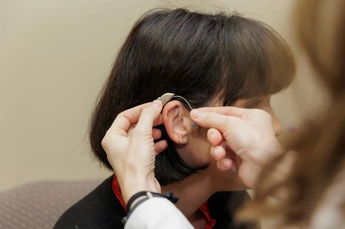 provider placing hearing aid on womans ear