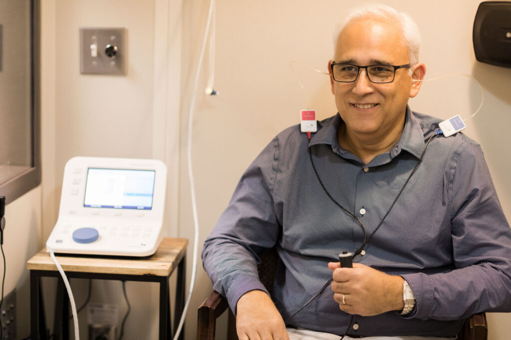 The Hearing Center man taking hearing comprehensive hearing assessment in sound booth