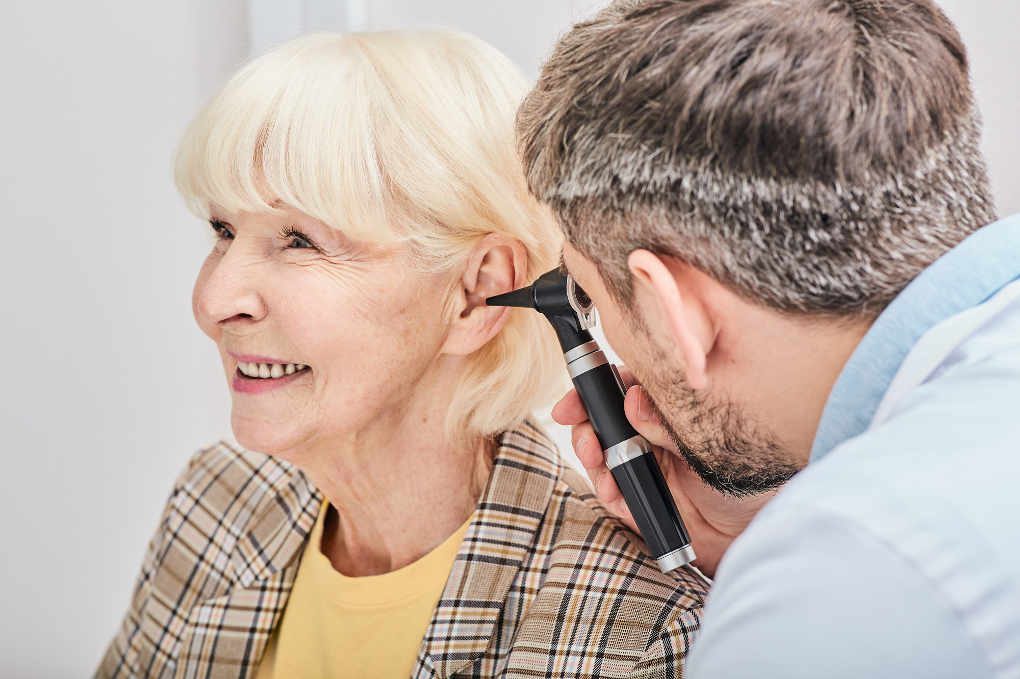 doctor looking into patients ear with otoscope