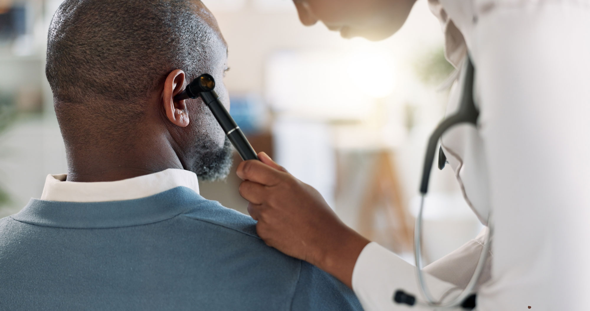 audiologist inspecting ear using otoscope on man