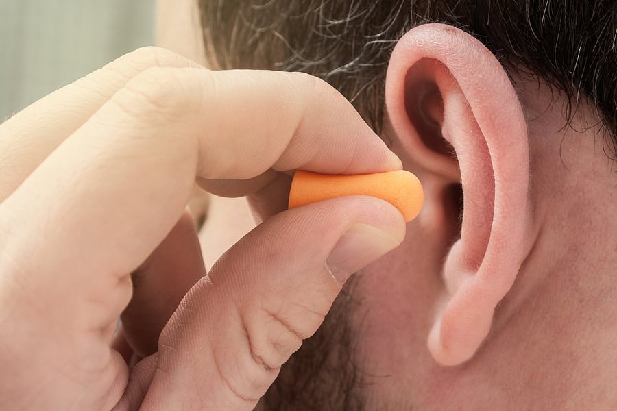 Man Putting Ear Plugs Into Ears To Protect Hearing And Get Rid O