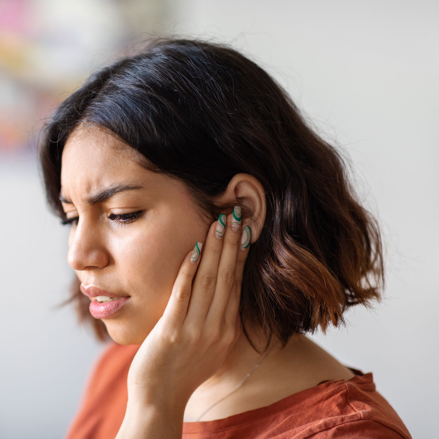 woman holding hand to ear due to ringing noise in ear