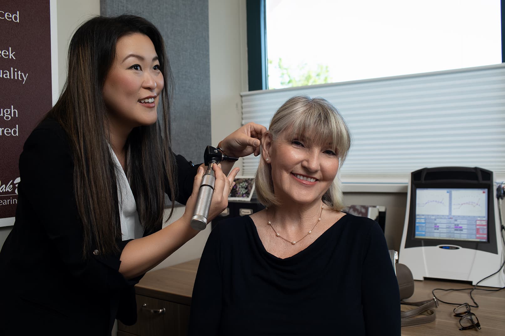 Vivien Brown inspecting patients ear with otoscope smiling