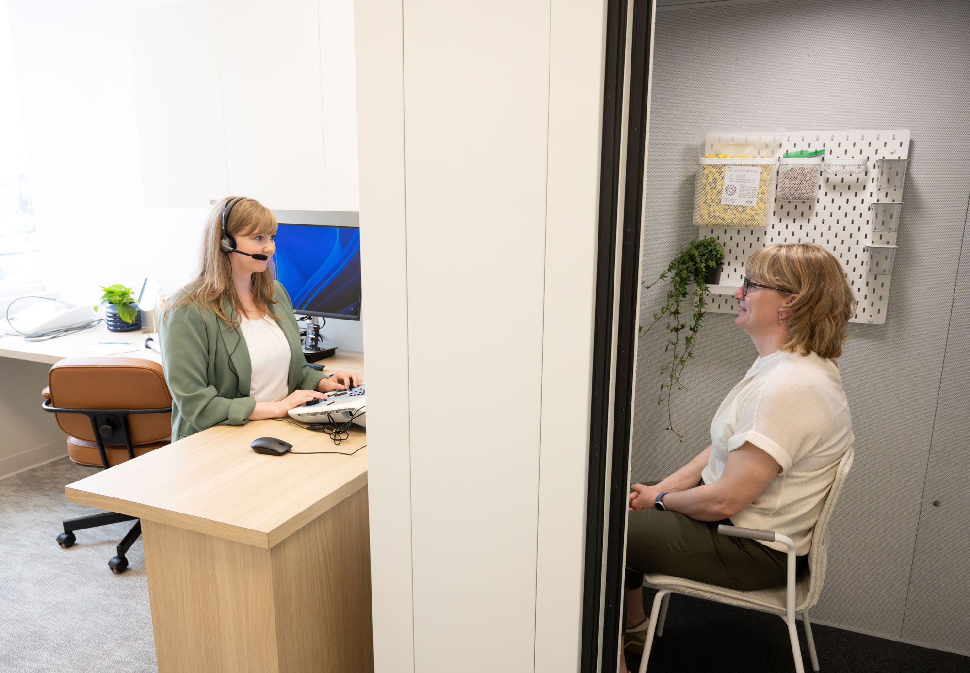 Veronica Gusikoski performing hearing test on patient in sound booth