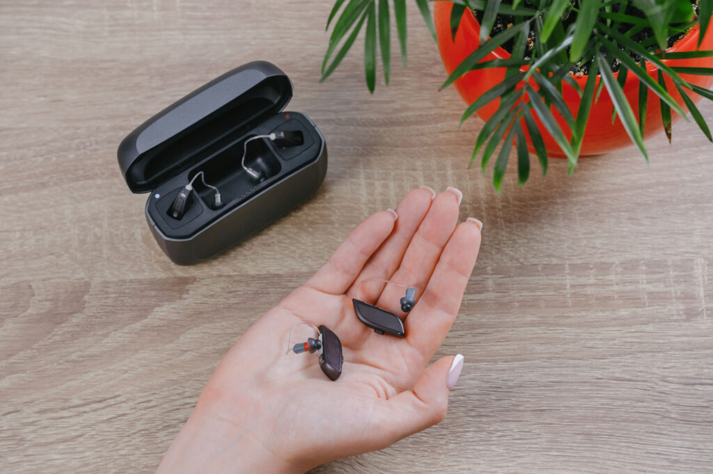 ric hearing aids in charger and womans palm