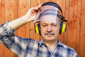 man wearing face and ear protection and plaid shirt