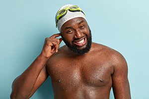 image of man wearing swim cap and goggles with water in his ear