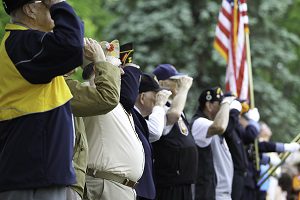 military veterans standing in a row saluting american flag