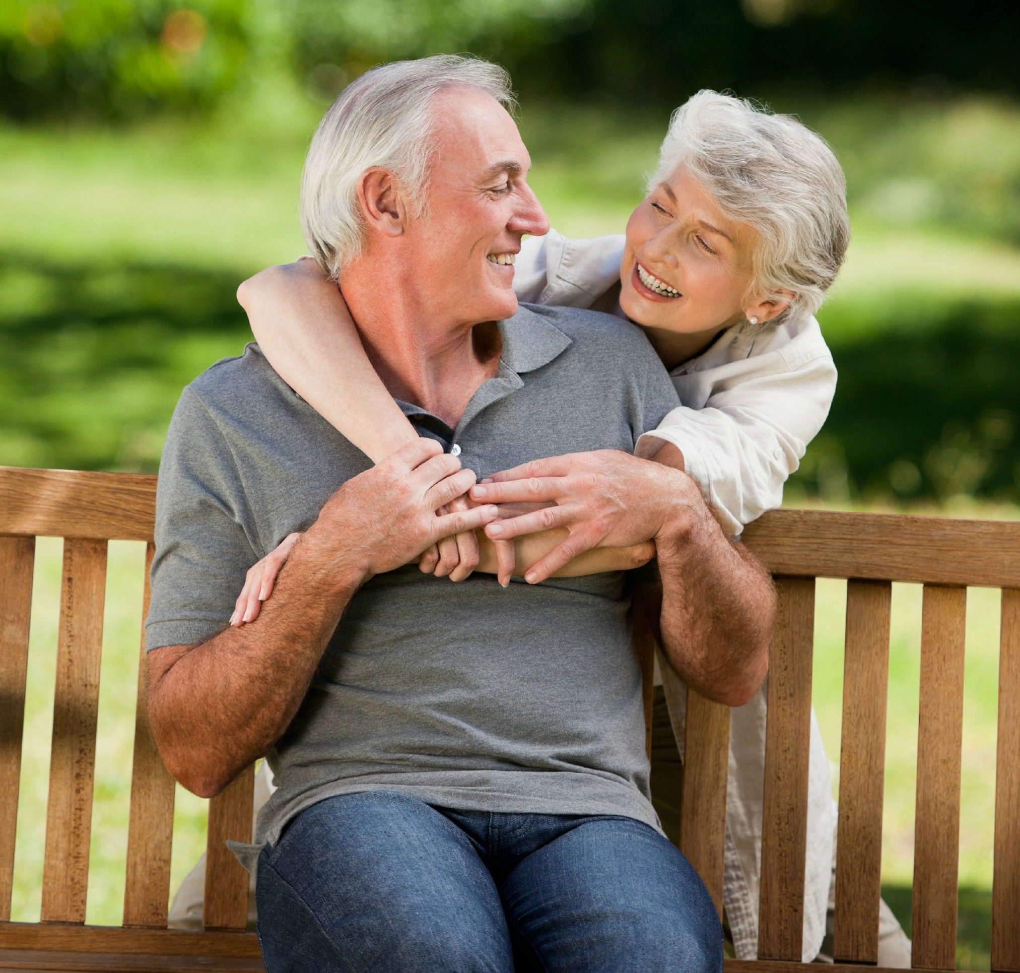 woman with arms around husband on bench