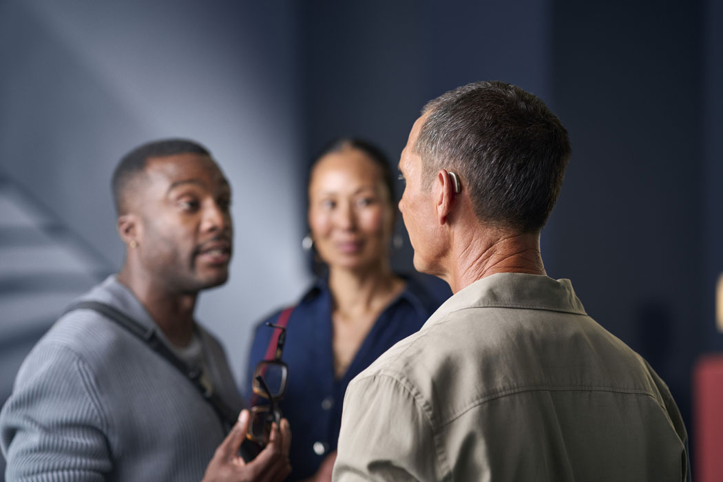 ReSound Savi lifestyle mature man with hearing aids talking in small group