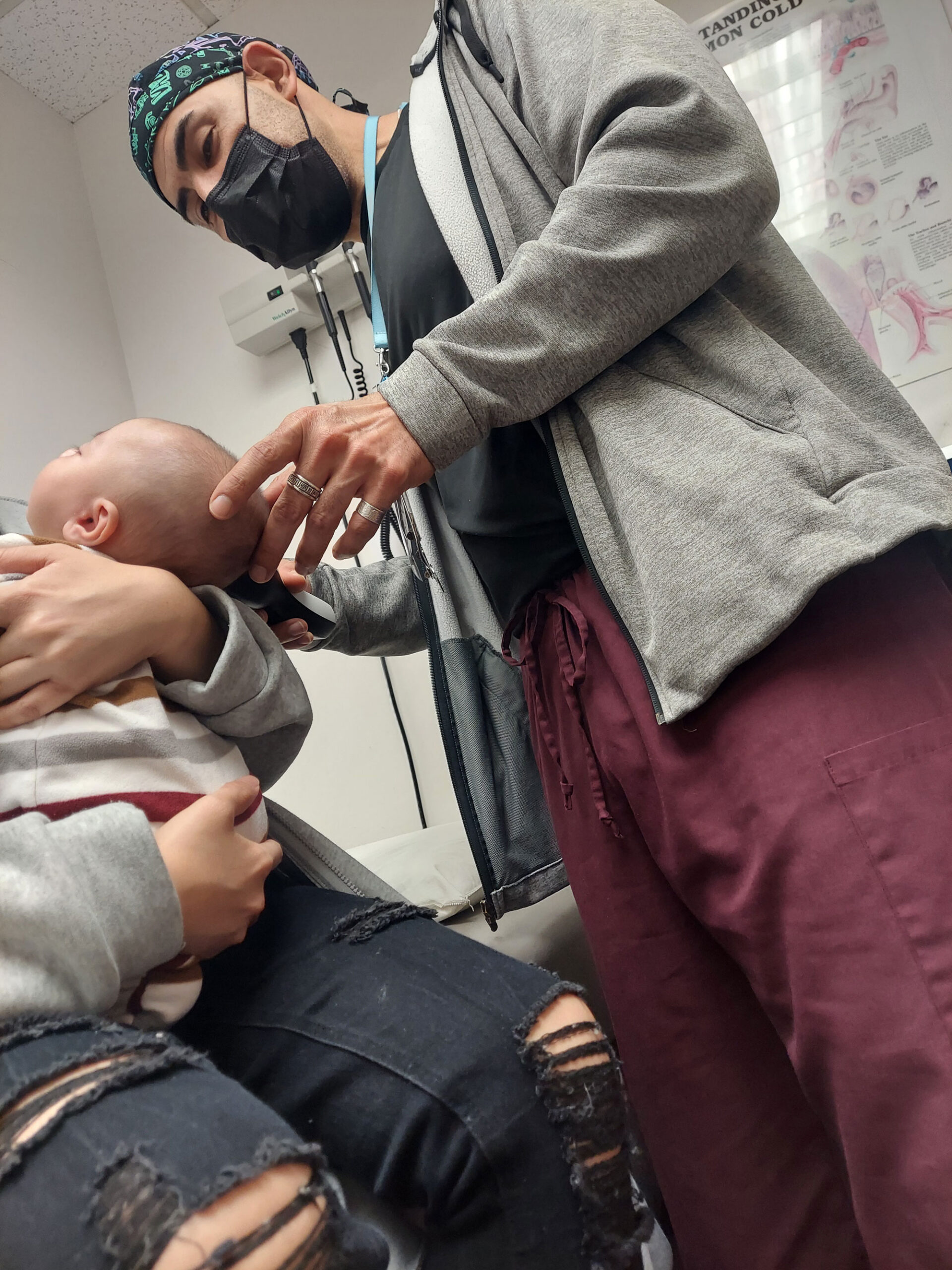 Andres Godinez Au D inspecting child patients ear