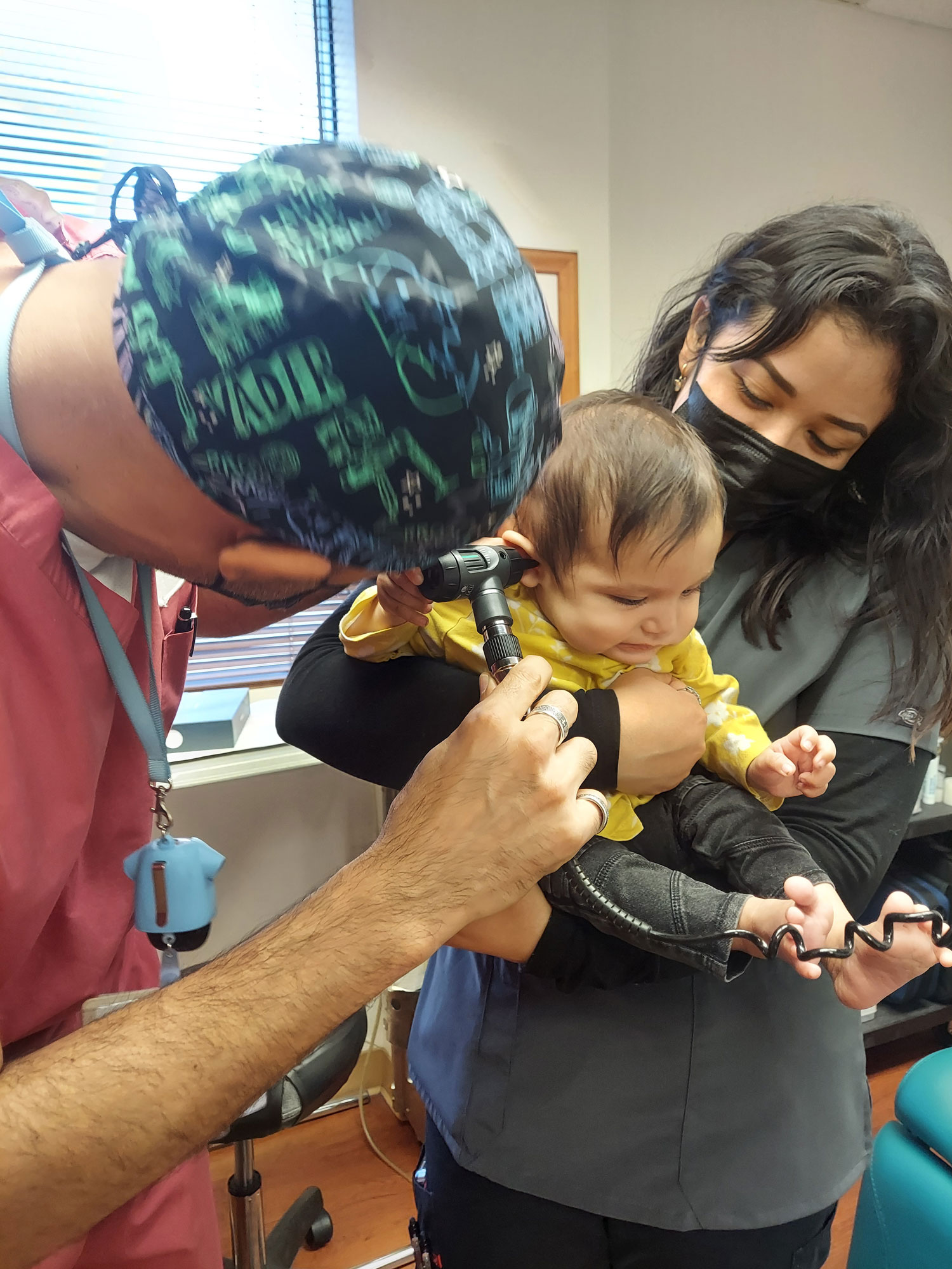 Andres Godinez Au D looking into baby patients ear otoscope