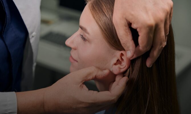 cta hover hearing care provider placing hearing aid on womans ear