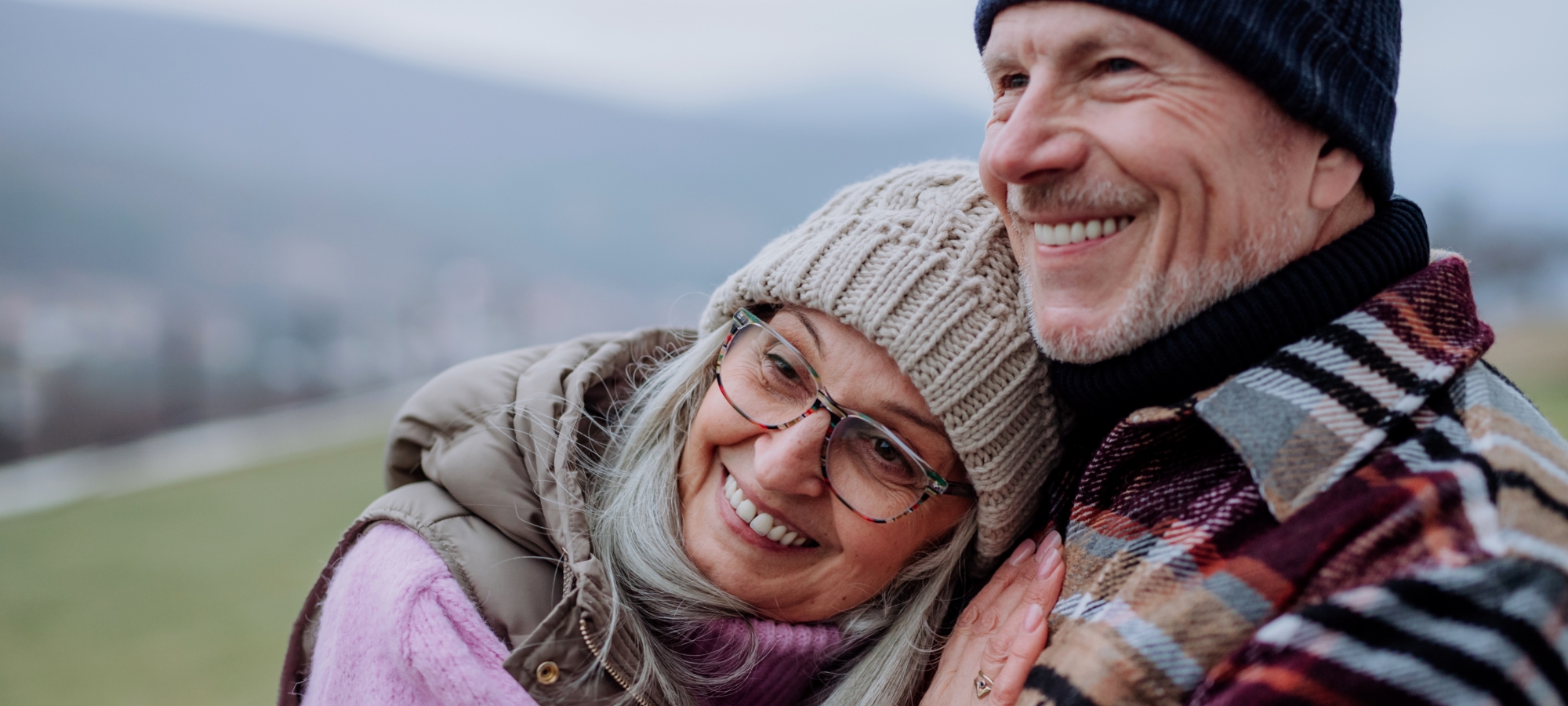 banner seasonal winter mature couple outside hugging smiling