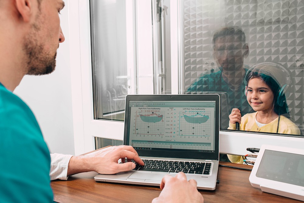 young child sitting in specialized room for hearing evaluation