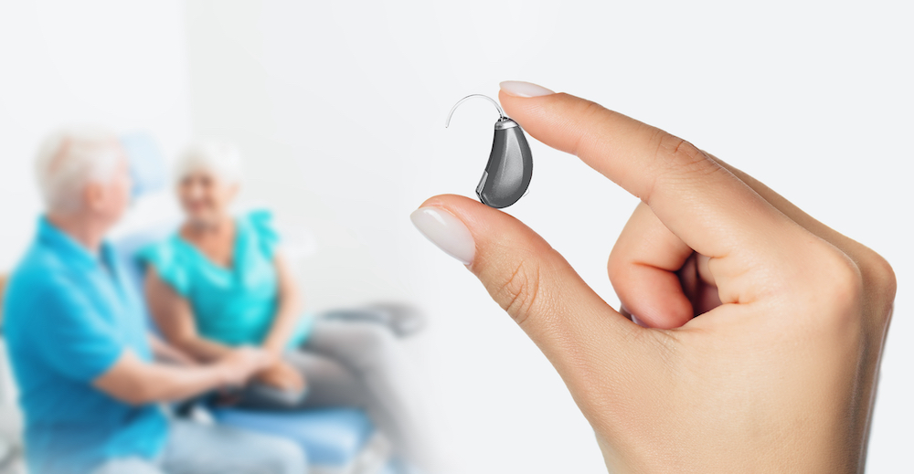 closeup image of hearing aid with two patients in background