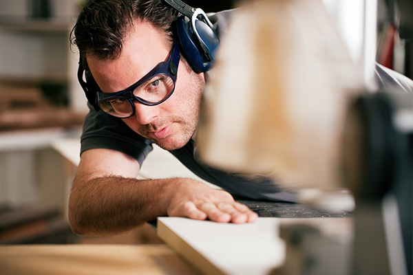 man cutting wood while using hearing protection