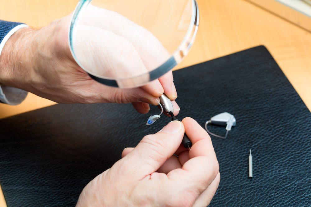 a hearing aid being professionally repaired under a magnifying glass