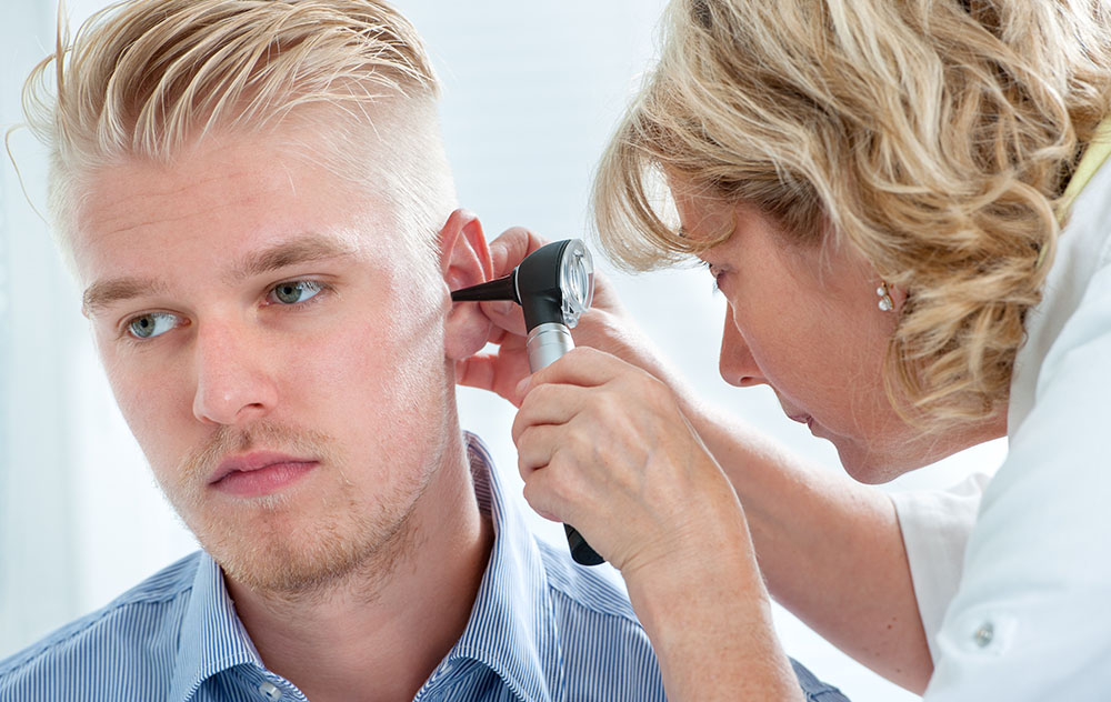 a blond haired man having his ears examined by a hearing specialist