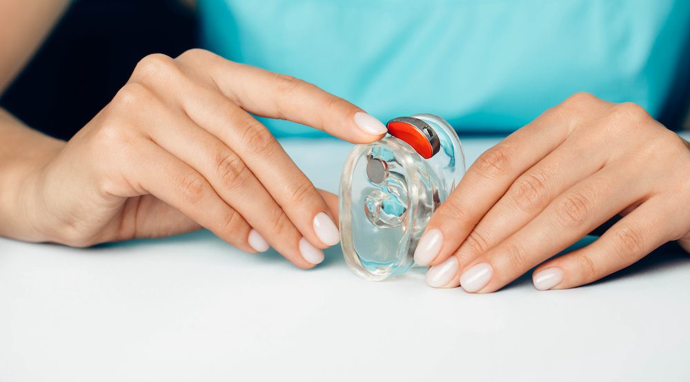 hearing aid specialist demonstrating the use of a premium red hearing aid