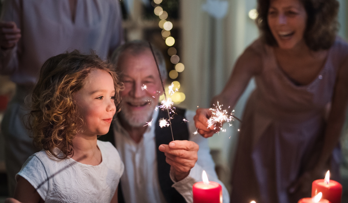 granddaughter admiring new years sparklers with grandparents