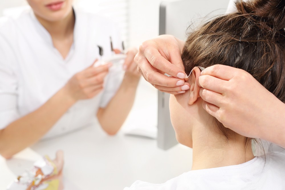 hearing specialist fitting patient with hearing aid devices