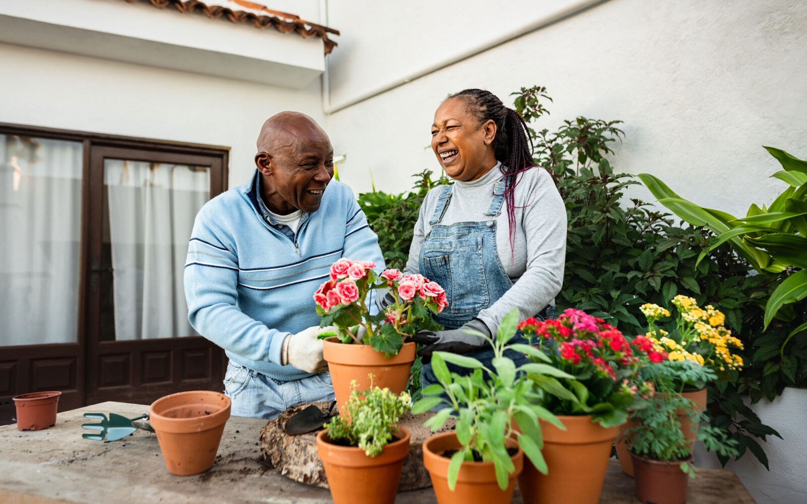 Happy African senior people gardening together at home