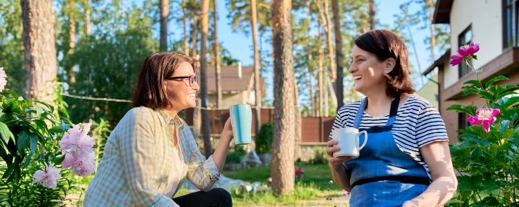 spring two friends enjoying coffe tea outside in garden spring two friends enjoying coffe tea outside in garden