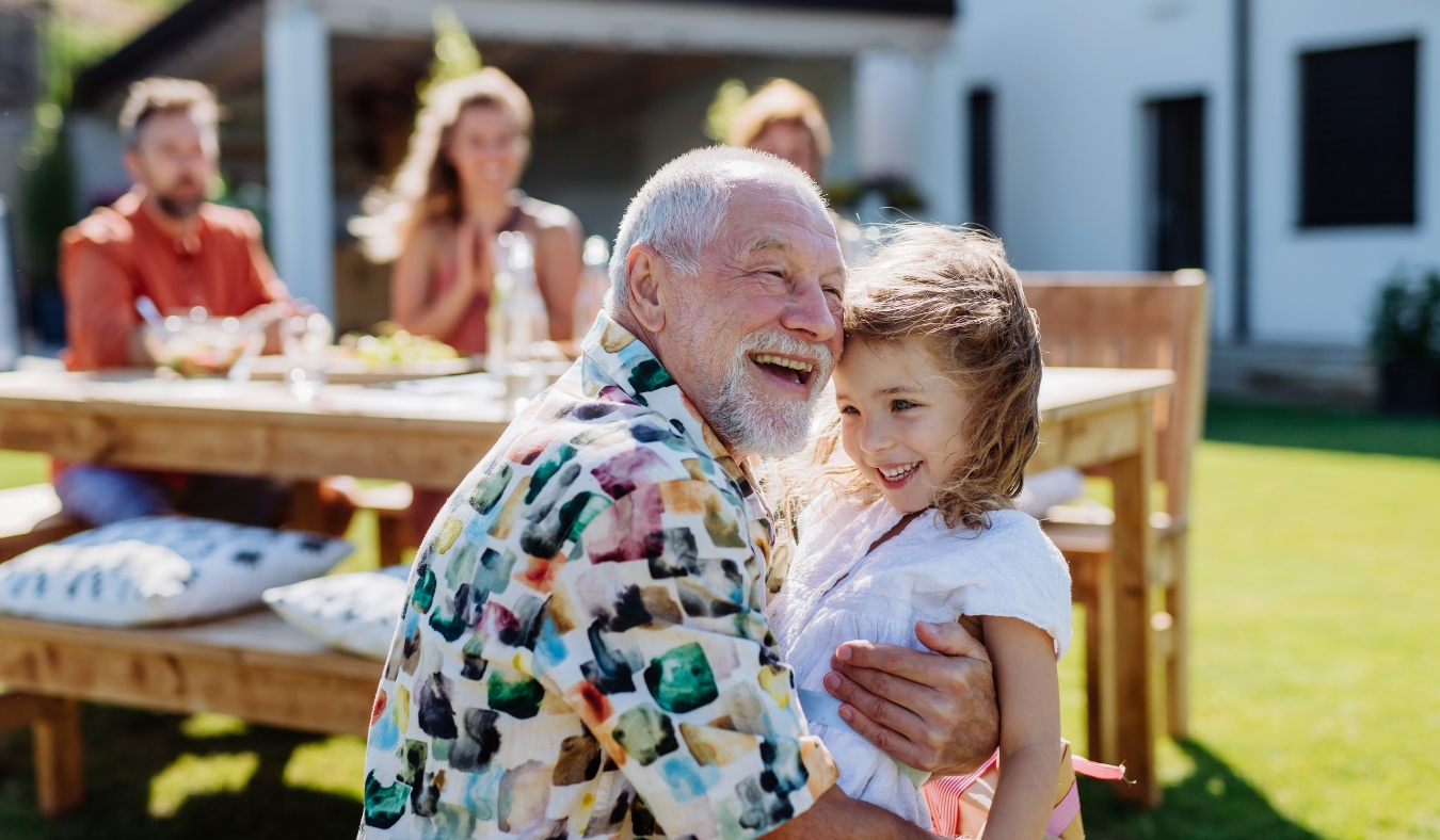 grandfather hugging granddaughter at family picnic birthday party
