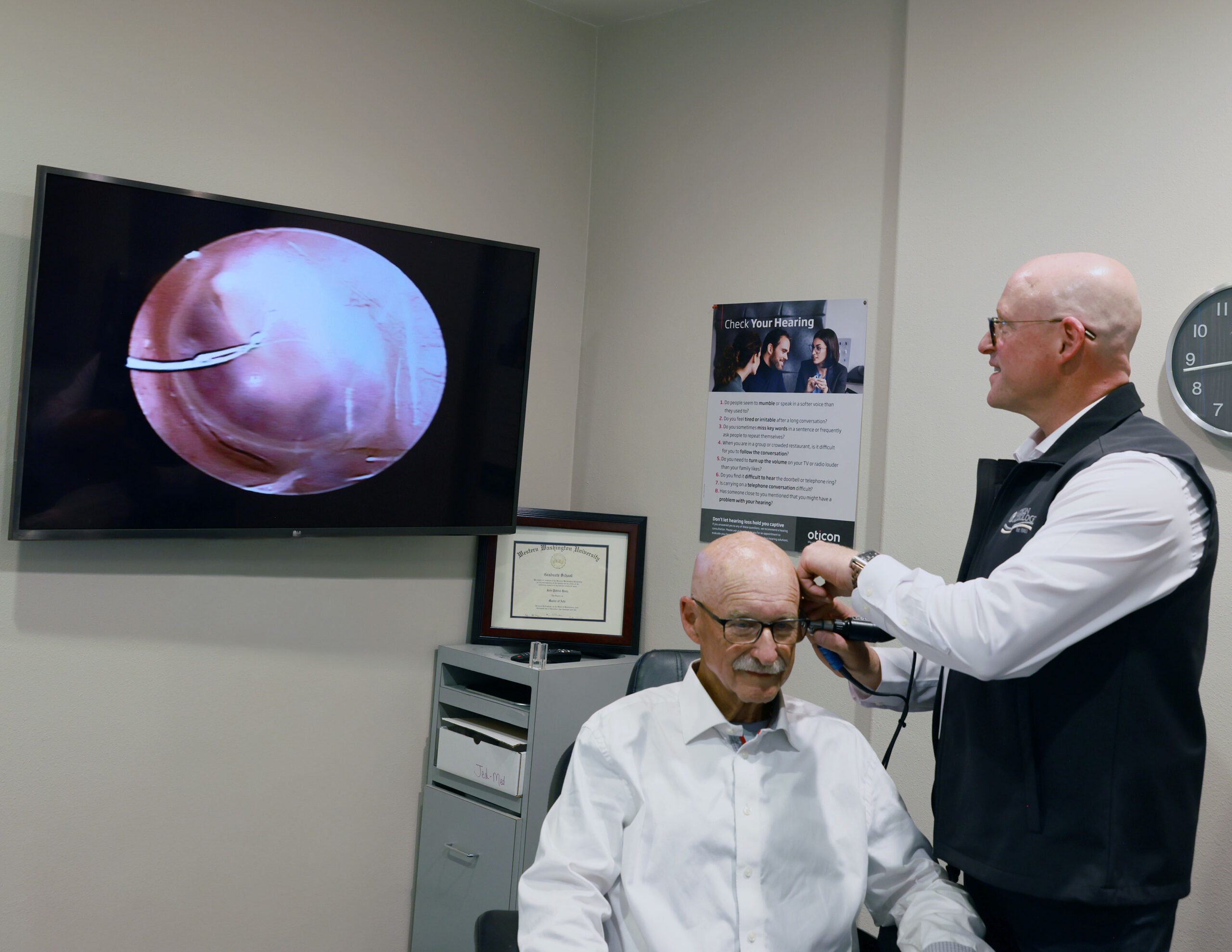 Audiologist inspecting patients ear