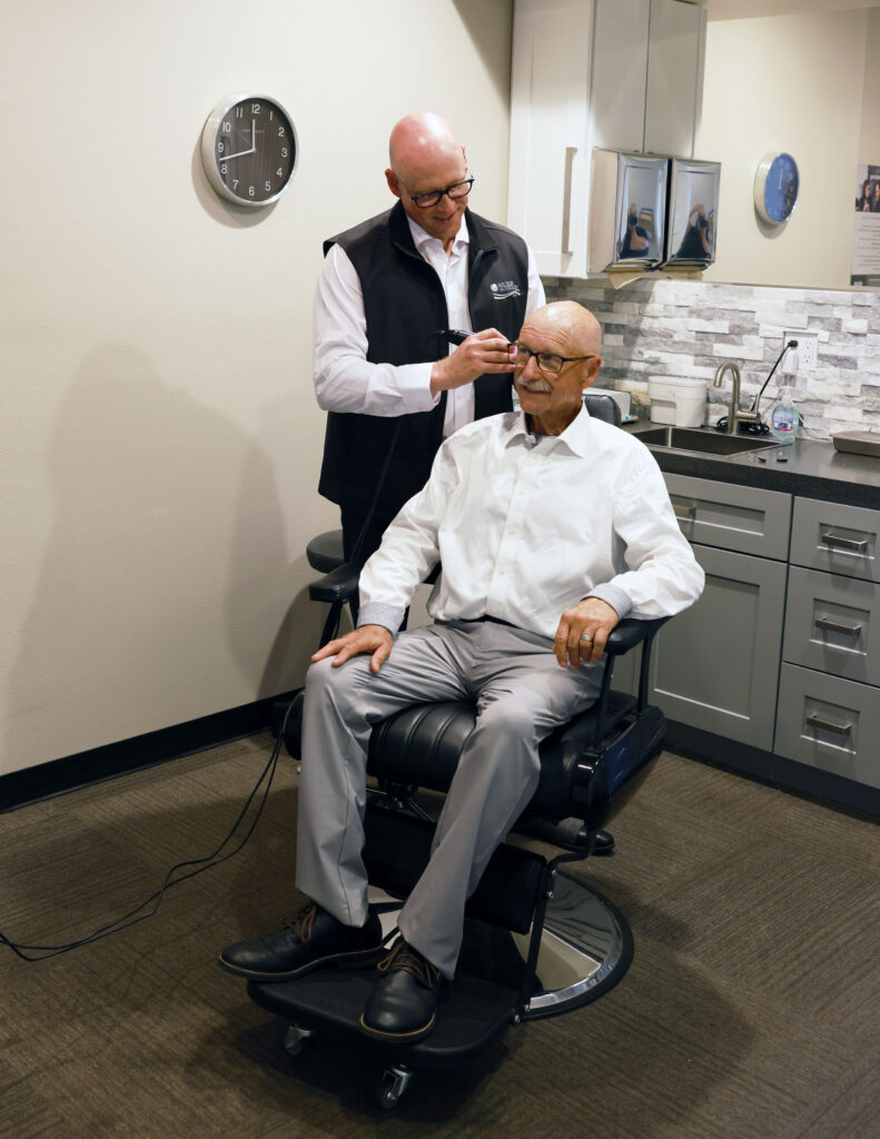 audiologist looking in patient ear with audiologic tool