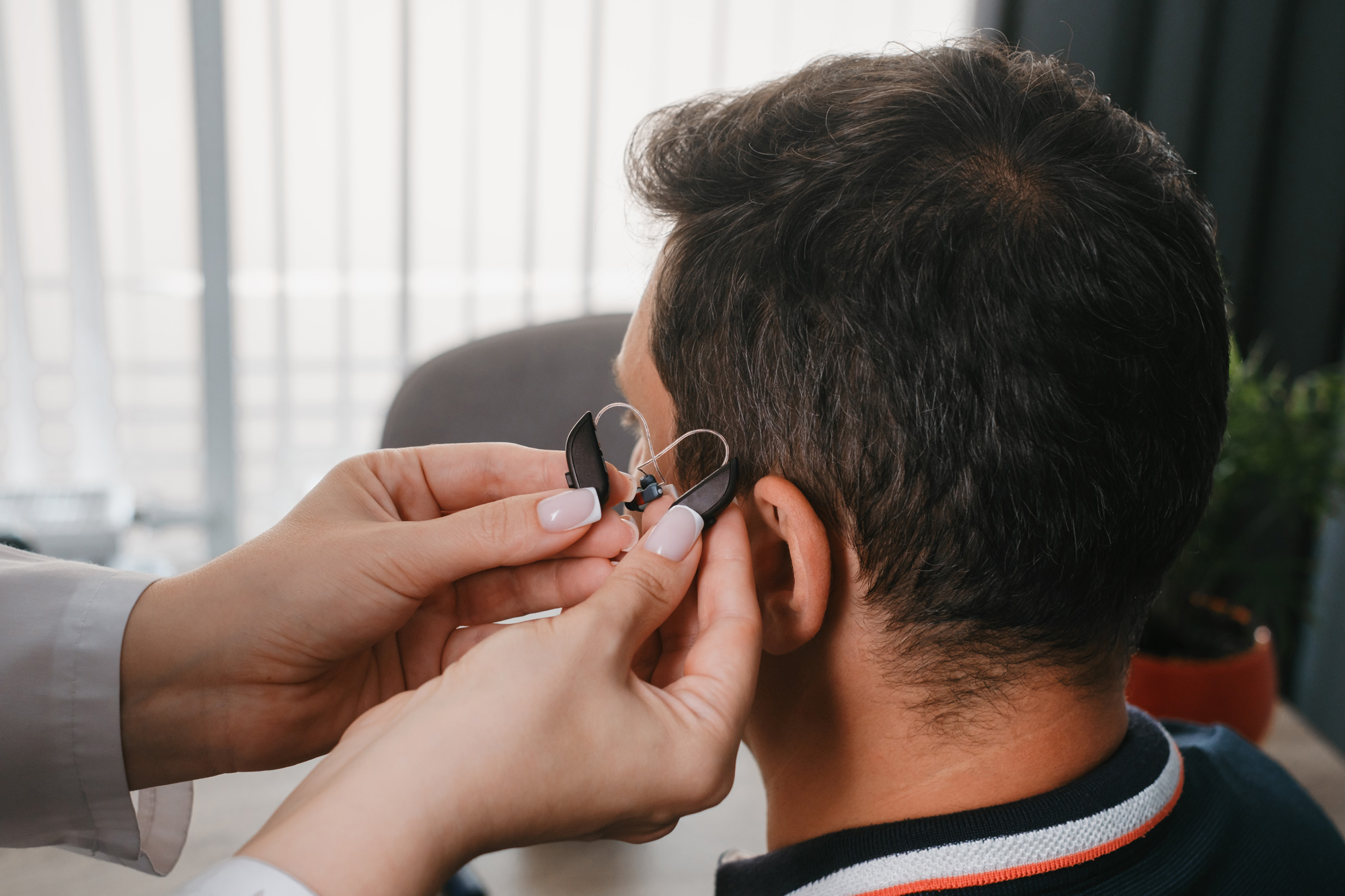 holding hearing aids to mans ear