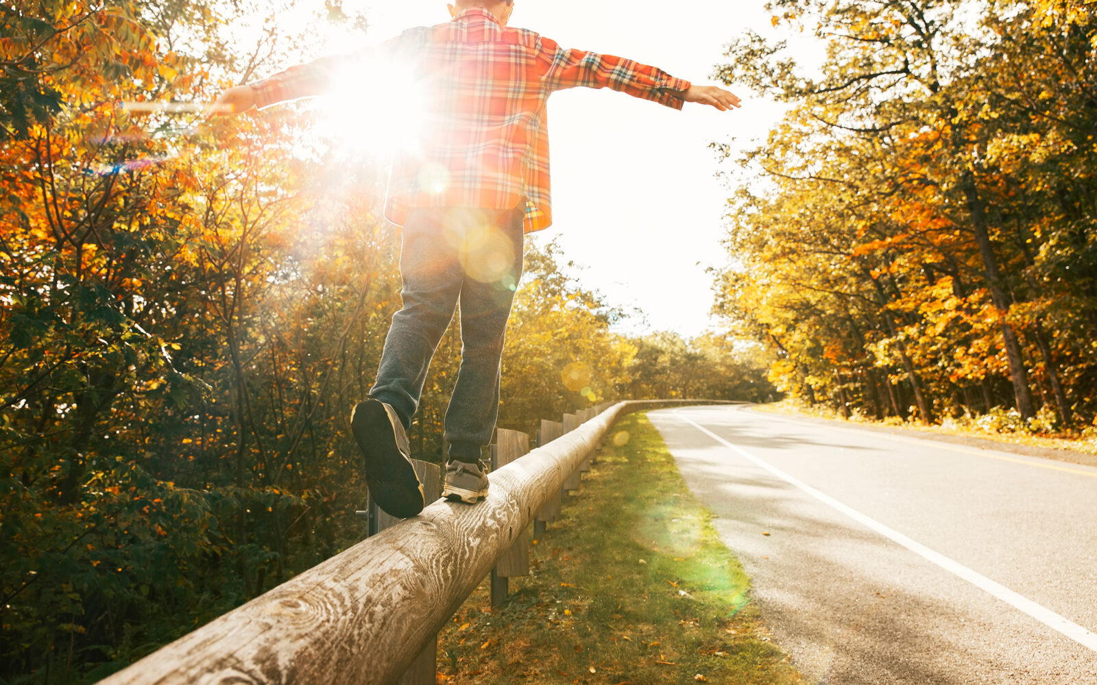 boy walking along the road fence child keeps balance on the log copy space for your text
