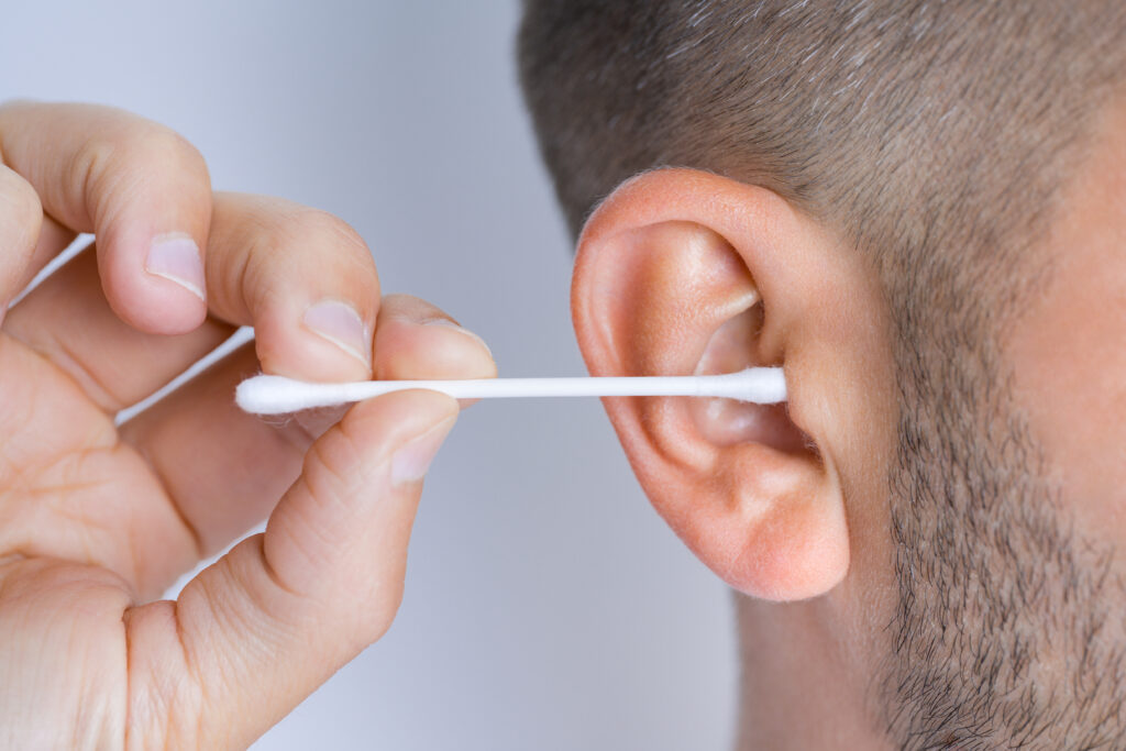 Closeup of man cleaning dirty ears with cotton swab or cotton stick Ear cleaning and ear care