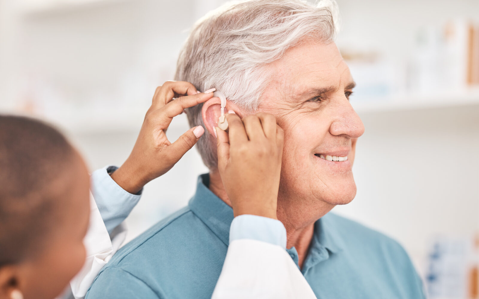 Helping, man and doctor with hearing aid, technology or healthcare or medical device consultation for deaf patient with tinnitus Listening, test and exam ear tech with nurse or senior male in clinic
