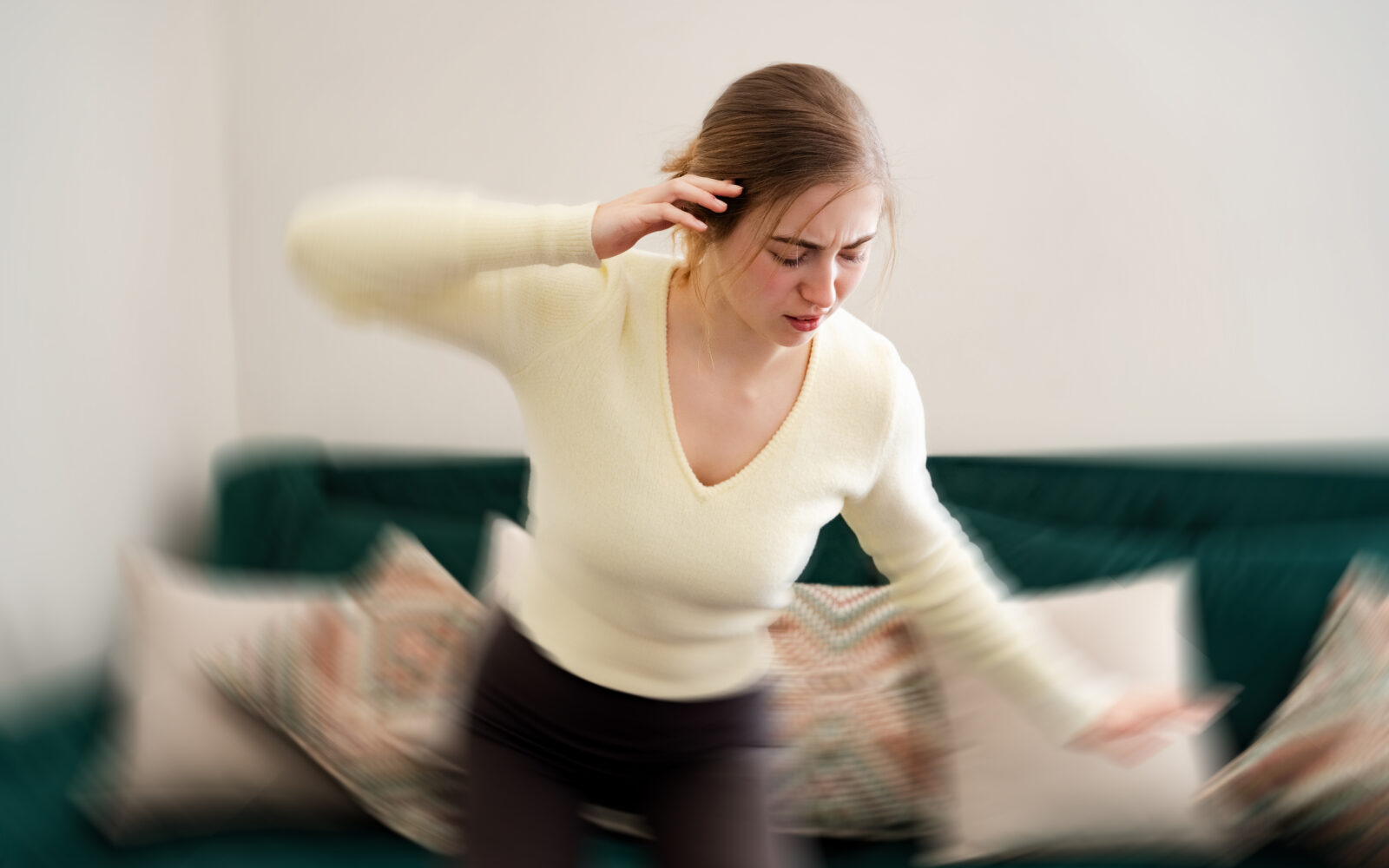 Young woman gets dizzy, loses her balance in the living room Tired girl with closed eyes having dizziness holding hand on head at home Vertigo disorder low blood pressure vestibular health problems