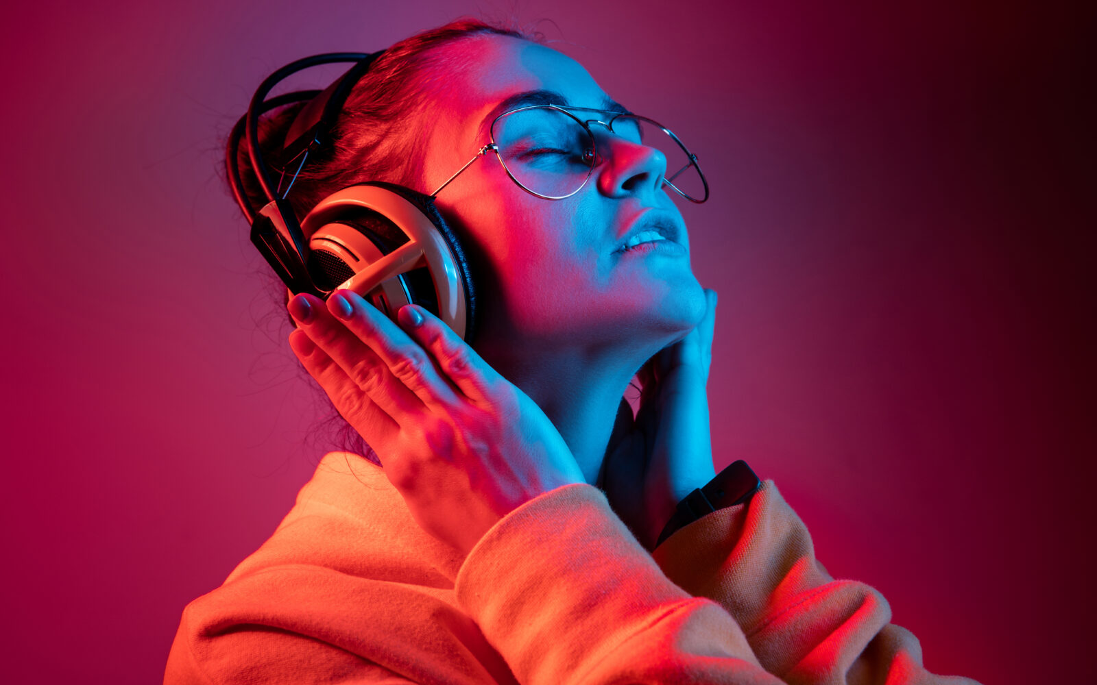 Fashion pretty woman with headphones listening to music over neon background