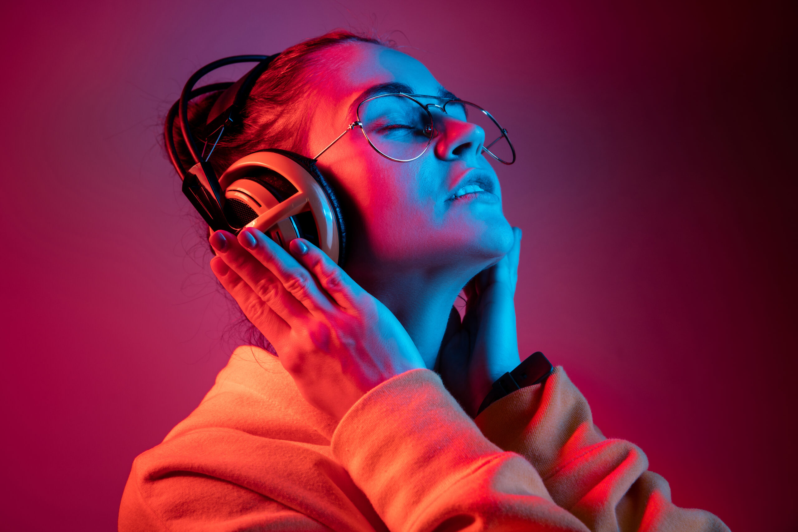Fashion pretty woman with headphones listening to music over neon background