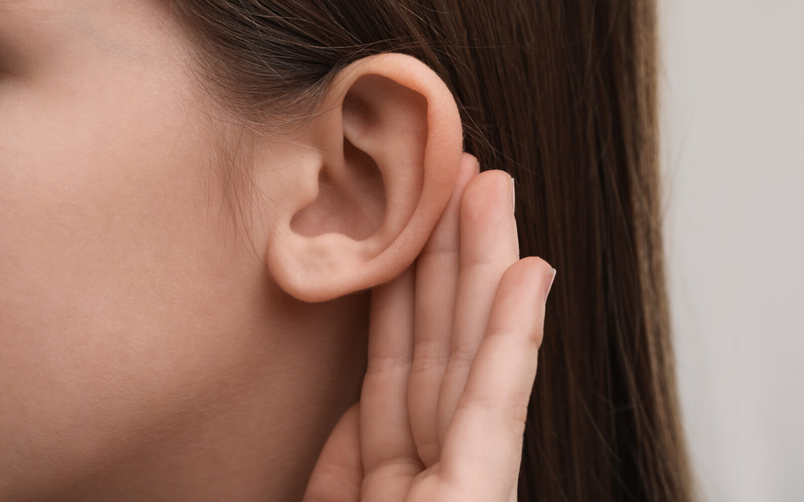 Little girl with hearing problem on grey background, closeup