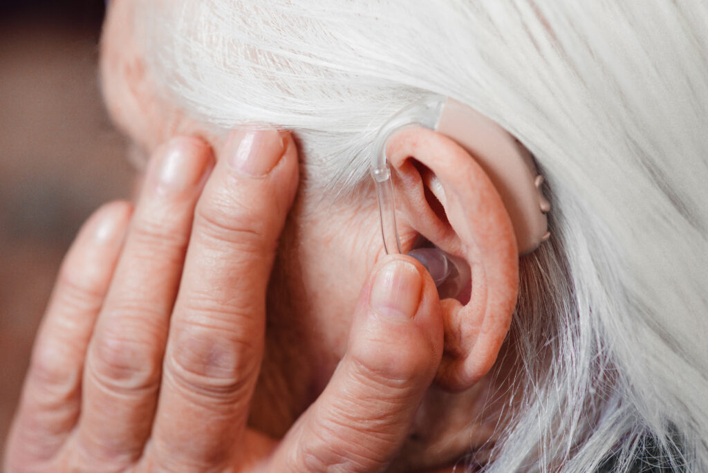 Closeup senior woman with hearing aid in her ear Health care, hear amplify, device for the deaf